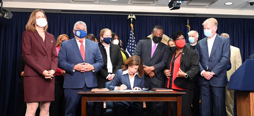 Gov. Kathy Hochul signs the Less Is More Act in 2021 surrounded by prominent district attorneys from around the state and former Lt. Gov. Brian Benjamin.